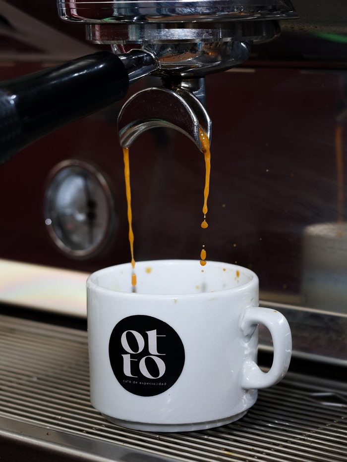 Café cayendo de la máquina a una taza con el logo del cliente
