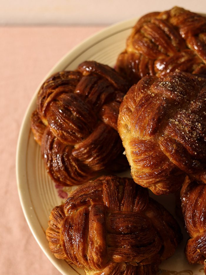 Toma cenital de croissants recién horneados sobre un plato claro, fondo rosa